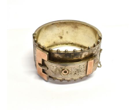 A LATE VICTORIAN SILVER BROAD 'BUCKLE' BANGLE the front with gilt accents, part foliate engraving and with beaded borders, Bi
