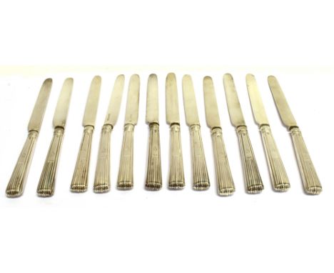 A SET OF TWELVE WILLIAM IV SILVER FRUIT KNIVES  with tapering fluted handles each engraved with a conforming crest in the for