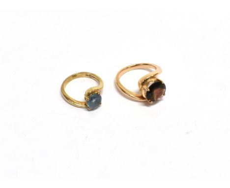 TWO MODERN GOLD AND ROUND GEM SET SINGLE STONE CROSS-OVER RINGS comprising; a green-ish-brown tourmaline ring, stamped '585',