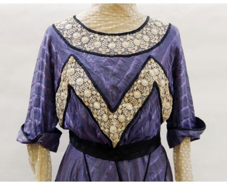 An early Victorian walking dress in purple silk, lace inset sleeves, bobbin lace and black satin detail around the neck and b