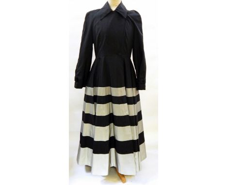 A Jasper Conran black coat dress, full skirted, the skirt banded in silver-coloured material, the cuffs with button and belt 