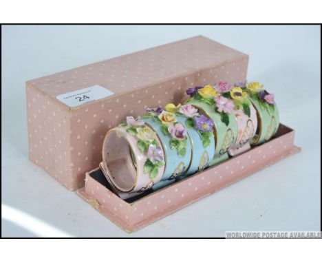 A cased set of mid century ceramic napkin rings embellished with floral sprays complete in the original box being stamped for