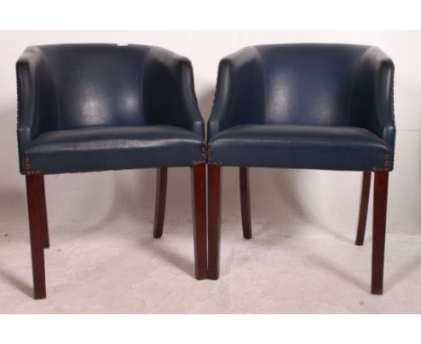 A pair of vintage 1950's working mens club armchairs raised on mahogany squared legs with blue vinyl seats. Measures: 75cm x 
