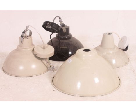 A collection of four contemporary retro style metal factory type pendant light fixtures, three in cream and the other in blac