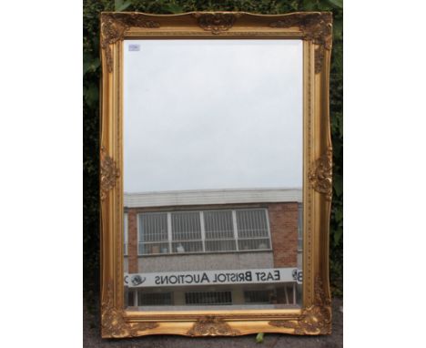 A contemporary antique style gilt framed wall mirror with bevelled edge central mirror. Measures: 106cm x 75cm.