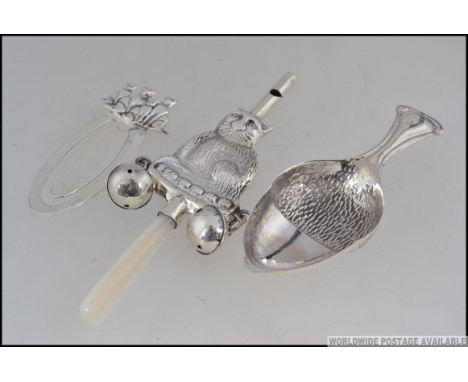 A silver babies rattle with whistle in form of cat , a silver bookmark and a silver tea caddy spoon in form of an acorn .  Me
