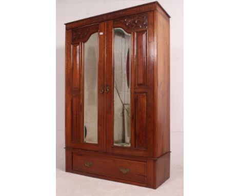 An Edwardian mahogany arts and crafts double wardrobe having plinth base with drawer and double mirror doors above. Cornice a