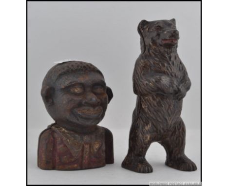 A vintage cast iron negro money bank with penny slot atop of head together with a cast iron money box in the form of a bear h