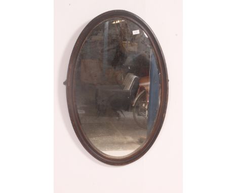 A large 19th century oval wall hanging mahogany framed mirror, having a bevel edged mirror panel. Measures: 90cm x 60cm.