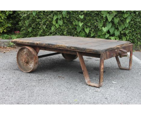 A vintage industrial early 20th century Bogie trolley having cast iron wheels with iron angular supports and  wooden top. Ide
