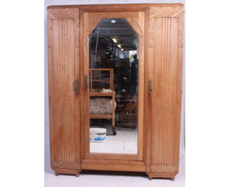 A 1930's Art Deco walnut breakfront  triple wardrobe. Raised on turned legs havnig decorative carved and embellished upright 