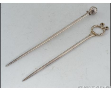 2 silver plated Tiffany & Co knitting needles, one with bow ribbon hoop end, the other with finial. Both marked Tiffany & Co,