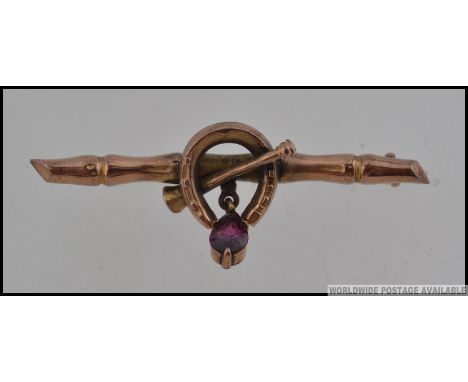 A Victorian 9ct gold sweetheart bar brooch with lucky horse shoe and hunting horn with amethyst drop and C clasp. Measures 4.
