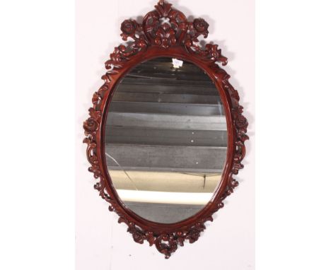 A good quality 20th century ornately carved wall hanging mirror, decorated with carved foliage with a central bevel edged mir