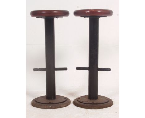 A pair of 1950's teak and tubular metal vintage bar stools with teak circular seats having metal frame and footrests. Measure