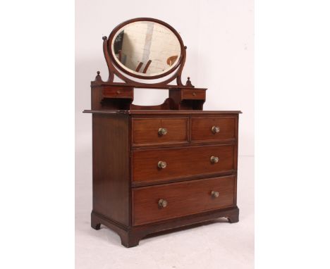 An Edwardian mahogany dressing table - chest of drawers having an oval swing mirror over short and deep drawer configuration.