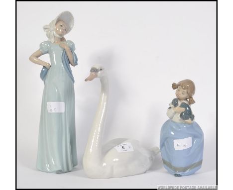 A boxed Lladro swan figurine together with 2 boxed Nao figurines, one of a child, the other a dame. Measures: swan 22cm H.