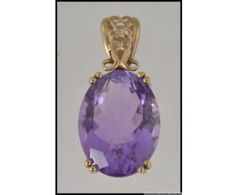 A large hallmarked 9ct gold pendant set with an oval cut amethyst in a prong setting with scroll decoration. Weight 5.3g Meas