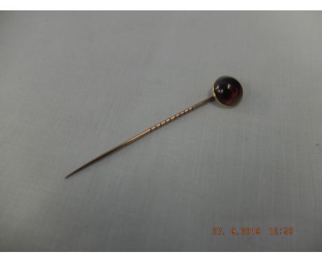 A yellow metal Cabochon garnet set stick pin