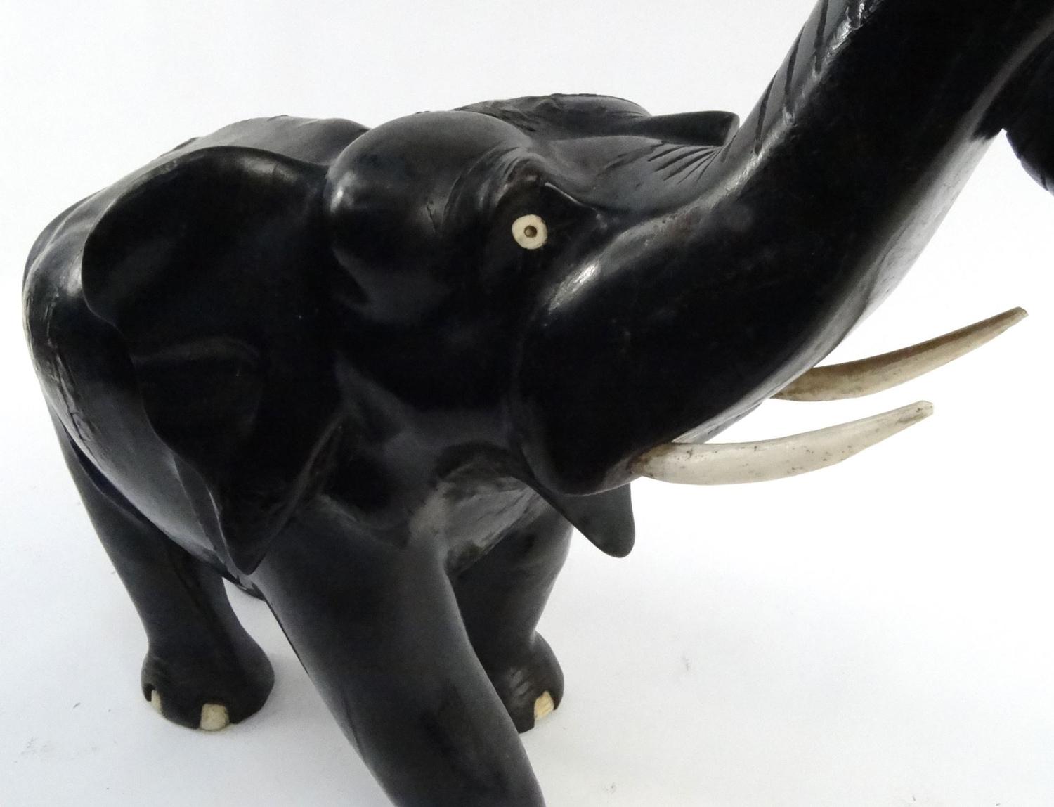 Large carved ebony elephant with ivory tusks, 55cm diameter :For