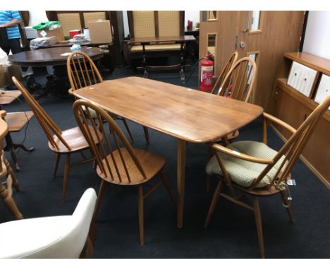 A light elm Ercol dining table, resting on square tapering legs together with a set of six spindle back chairs including two 