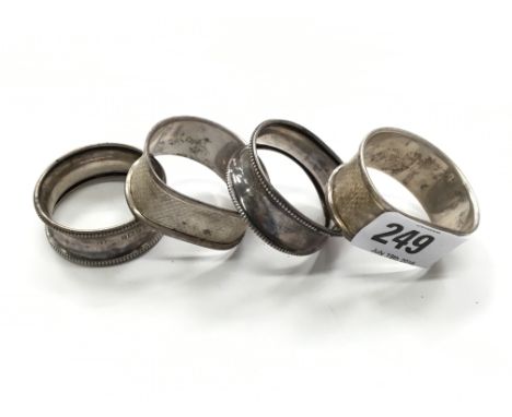 Four silver serviette rings together with a small squat silver candlestick.