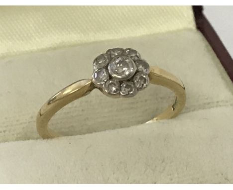 A vintage Art Deco style 18ct diamond set dress ring of flower head design. Central round cut diamond surrounded by 8 smaller