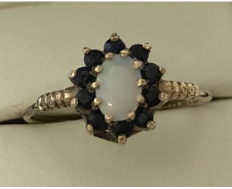 A 9ct gold sapphire and opal dress ring. Central oval cut opal surrounded by 10 small sapphires. Ring size Q. Total weight ap