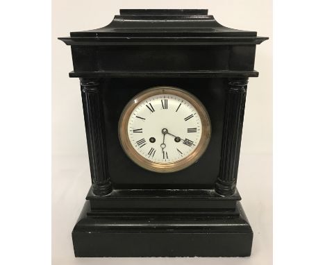 A Victorian black slate mantle clock with column detail. Enamelled face with roman numeral markers and bevel edged glass. Com