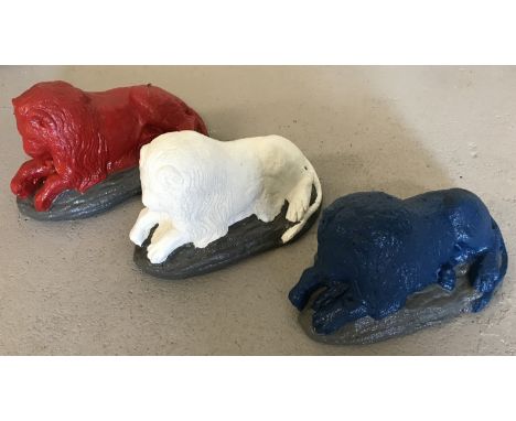 3 stone garden ornaments in the shape of laying lions, painted in red, white and blue colours. Each approx. 15cm tall x 29cm 