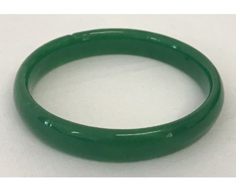 A bright green jade type bangle, approx. 7.5cm diameter.