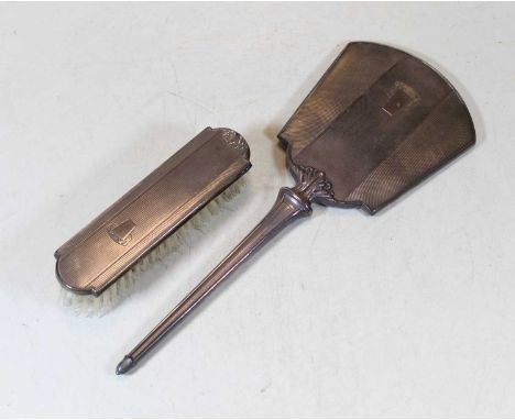 An Art Deco silver backed hand mirror, having engine turned decoration; together with a similar silver backed brush (2)
