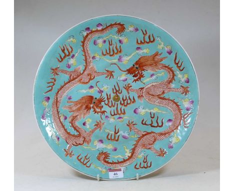 A Chinese stoneware charger, on a turquoise ground, enamel decorated with two five-claw dragons chasing a mythical pearl amid