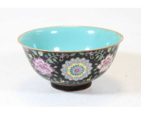 A Chinese famille noir rice bowl, enamel decorated with various flowers, having a turquoise interior, with blue seal mark ver