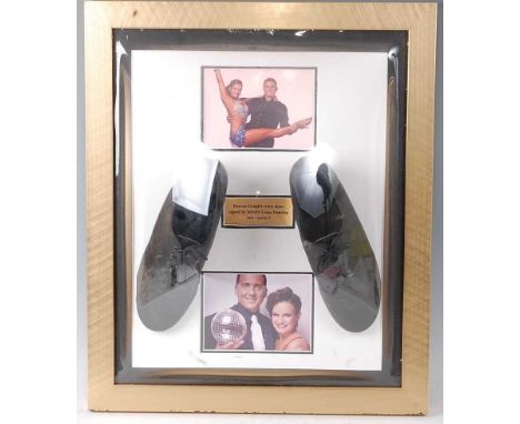 A pair of black leather shoes bearing various signatures in gold ink, mounted for display with plaque "Darren Gough's worn sh