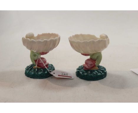 A pair of circa 1900 Royal Worcester salts, each in the form of a shell raised upon a dolphin's back and on a circular base, 