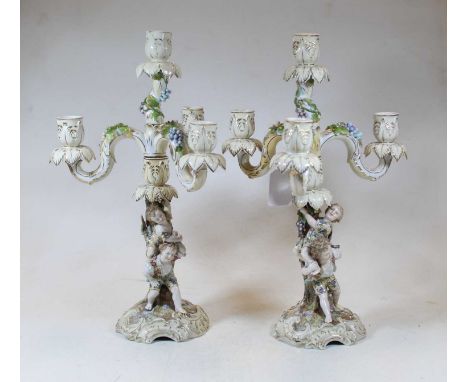 A pair of late 19th/early 20th century continental porcelain candelabra, each having three floral encrusted sconces supported