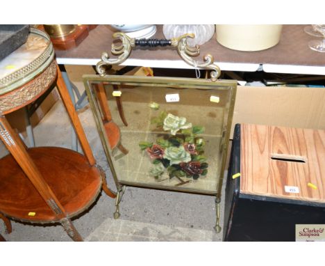 A brass and mirrored fire screen with floral decoration