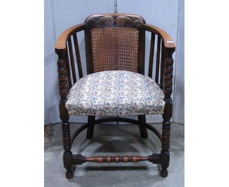 A 1920s tub chair, with stained beechwood frame, cane panelled back with carved detail, slatted open sides, upholstered seat,