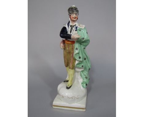 A 19th century Staffordshire figure of a theatrical character in spotted green cloak, possibly representing a Cossack, raised