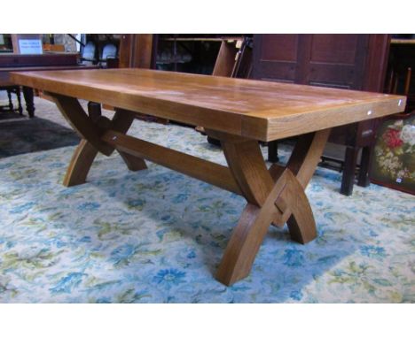 A good quality contemporary light oak dining table of rectangular form raised on X framed supports, united by a central stret