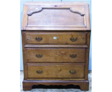A medium to light oak writing bureau, the moulded panelled fall flap enclosing a simply fitted interior over three long gradu
