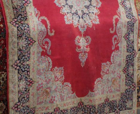 Belgian carpet with central blue and pink floral medallion upon a red ground, 310 x 210cm