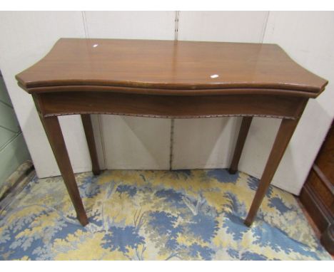 An Edwardian mahogany fold over top card table of serpentine form in a Georgian manner raised on square taper and moulded sup