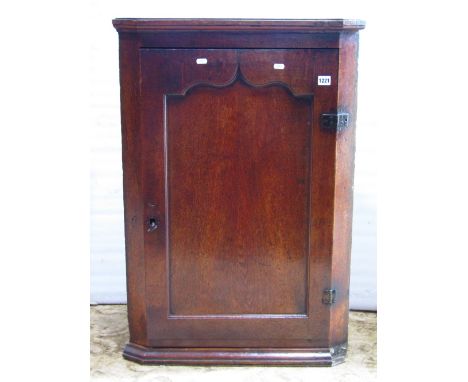 A Georgian oak hanging corner cupboard enclosed by a rectangular moulded pointed arch panel door, the interior painted and fi