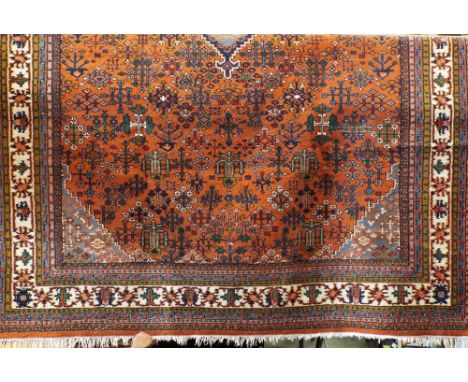 A good quality Indian carpet decorated with a central blue medallion decorated with various geometric motifs upon an orange g