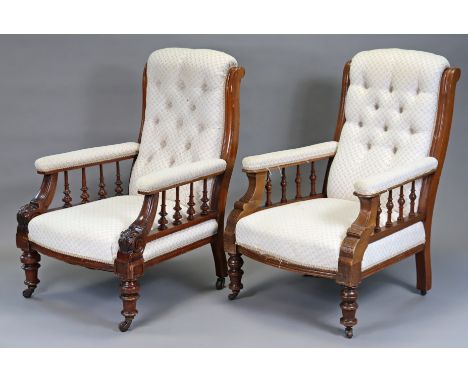 A near pair of Victorian mahogany frame easy chairs, each with spindle supports, down-swept arms and turned legs with ceramic