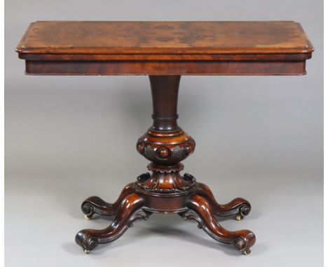 A mid-Victorian figured walnut card table, the rectangular fold-over top inset circular crimson baize, on a turned and carved