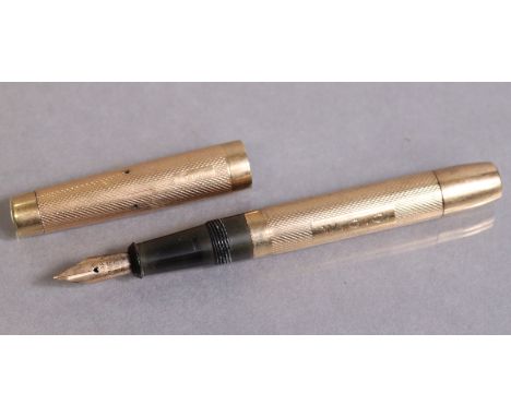 A De La Rue Ltd. 9ct gold engine-turned fountain pen with 14K nib, 11cm long; London hallmarks for 1934. (6.4gm weighable).