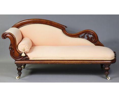 A Victorian mahogany chaise longue upholstered in peach fabric with repeating pattern and gold ribbon border, all-over carved